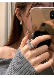 Detail view of a luxury zircon bow ring and pearl earring worn by a female model
