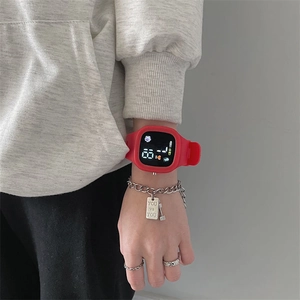 Close-up of red digital watch with square dial and silicone strap on female wrist