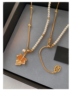 Detail view of gold-plated maple leaf pendant with pearls and amber crystal stones