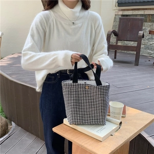 Detail of wool houndstooth bento bag with magnetic clasp and woven black handle