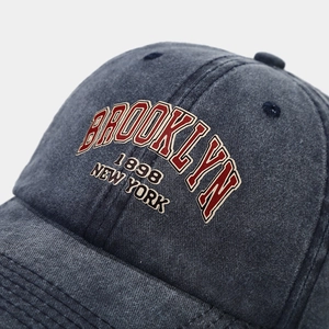 Close-up of high-density Brooklyn embroidery on washed grey cotton canvas baseball cap