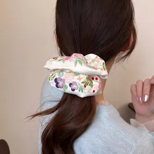 Elegant satin hair scrunchie with floral embroidery worn on a ponytail ponytail