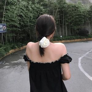 Detailed view of a cream white satin rose flower scrunchie styled on a low ponytail