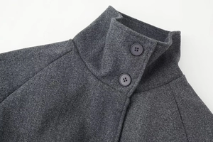 Dettaglio cappotto in lana grigio scuro con collo alto e chiusura a due bottoni