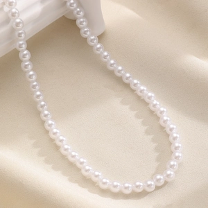 Classic white imitation pearl necklace detail close-up showcasing smooth round bead texture.