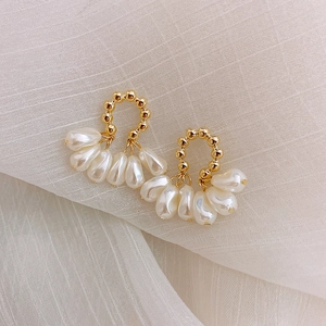 Macro view of French vintage pearl earrings with golden beads on a soft fabric texture