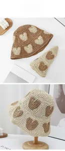 Detailed view of foldable straw sun hats with woven heart patterns in neutral tones