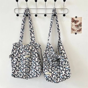 Detail of cream-white butterfly print canvas tote bag and shoulder bag on wall hangers