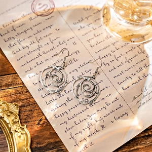 Detail of bohemian spiral engraved earrings in antique silver finish on vintage paper