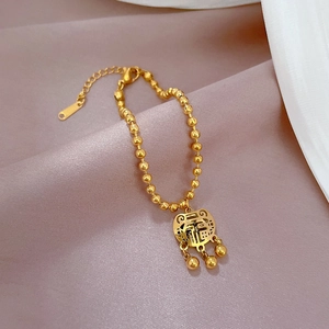 Macro view of gold beaded bracelet with Fu character lock pendant and tassels on silk