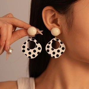 Retro acrylic geometric square earrings with black and white polka dots on a model