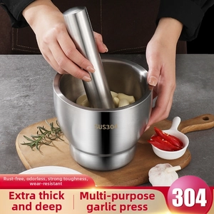 Macro detail of hand using 304 stainless steel mortar and pestle for crushing fresh garlic