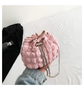 Detailed close-up of pink pleated bucket bag with silver chain strap and pearl decor