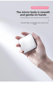 Macro view of ultra-thin silver foldable makeup mirror held in hand showing metallic finish