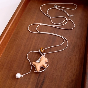 Detailed shot of wooden rocking horse pendant on silver chain with tiger eye bead