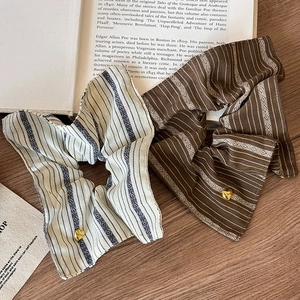 Retro striped scrunchies set with golden heart pendants on vintage book background