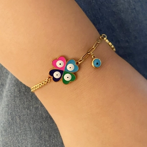 Detailed view of gold bracelet with colorful evil eye heart clover charms on a wrist