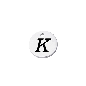Close-up of polished stainless steel circular charm with engraved capital letter K