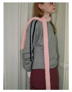 Detail shot of a thick pink knit scarf draped elegantly on a model for winter warmth