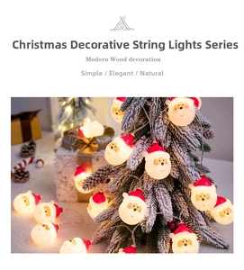 Close-up of Santa Claus LED string lights with warm yellow glow on a snowy Christmas tree