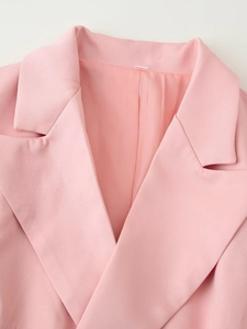 Detail view of a pink blazer's notched lapel featuring fine woven texture and smooth finish