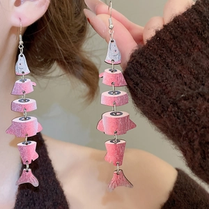 Close-up of pink wooden fishbone drop earrings with a flexible multi-section design
