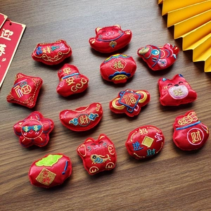 Close-up of Lunar New Year plush charms including lucky cat and gold ingot embroidery