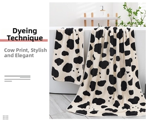 Detail of high-density cow print coral fleece bath towel set on a bathtub edge