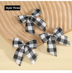 Set of 3 black and white plaid Christmas bows displayed on a rustic wooden tray