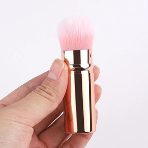 Portable retractable makeup brush with pink bristles and rose gold handle for travel