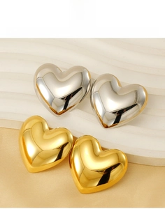 Macro detail of 18k gold and silver heart stud earrings in durable titanium steel