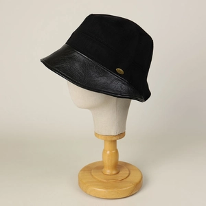 Women's black cotton bucket hat with leather brim and gold metal brand tag detail