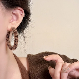 Gros plan de boucles d'oreilles rondes vintage à imprimé léopard portées par un mannequin