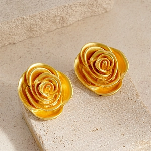 Macro detail of golden rose petal earrings with vintage matte texture and layered design