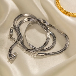 Polished silver stainless steel snake bone chain necklace on elegant silk background