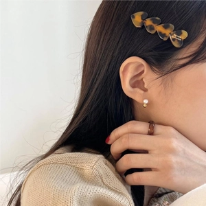 Detail of tortoise shell heart hair clip with gold lettering on a female model