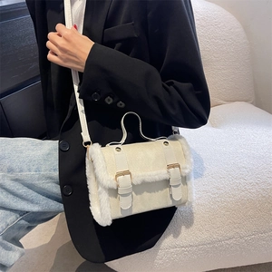 White faux fur trim crossbody bag with leather straps on a seated model in a black blazer