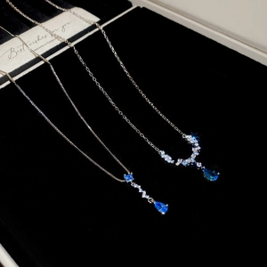 Close-up of silver pendant necklaces with blue teardrop stones in a black velvet box