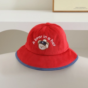 Détail d'un chapeau bob pour enfant en velours rouge avec broderie ours et liseré bleu