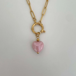 Close-up of golden spring clasp necklace with a polished pink heart glass pendant