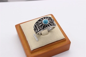 Détail d'une bague vintage en acier pour homme avec turquoise ronde et motifs solaires