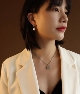 Detailed view of elegant silver pendant necklace and pearl earrings on a female model