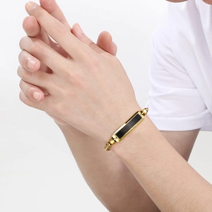 Herrenarmband aus goldenem Edelstahl mit schwarzer Einlage am männlichen Handgelenk