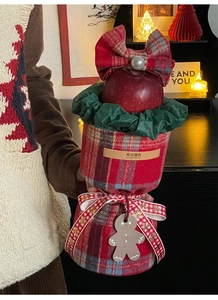 Close-up of red plaid Christmas apple gift bag with bow and wooden gingerbread man tag