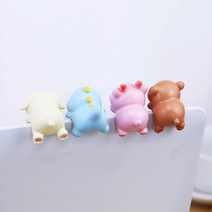 Rear view of four colorful mini animal figurines hanging on a laptop screen edge