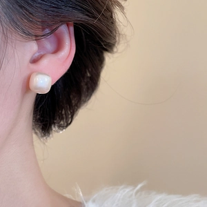 Close-up of cream square earrings with pearl luster on model for a vintage look