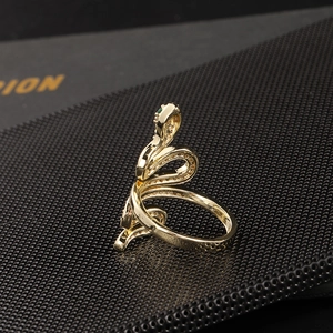 Detail of golden snake ring featuring green gemstone eyes and pavé-set crystals