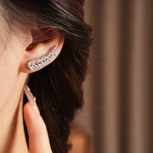 Close-up of a silver wheat leaf ear cuff with sparkling zircons on a model's ear