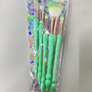 Five-piece mint green makeup brush set with rose gold ferrules in a glitter pouch