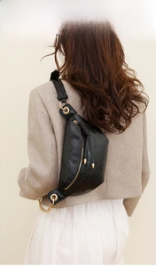 Details der schwarzen Leder-Brusttasche mit goldenem Reißverschluss zum beigen Anzug